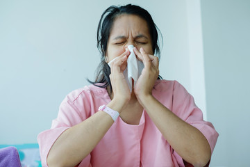 Sick Asian woman using a tissue.