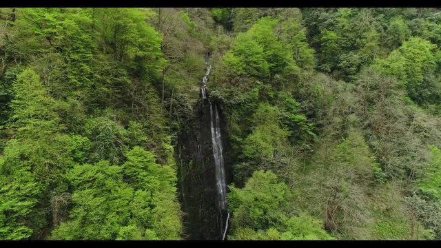 Rising aerial motion view of a waterfall in a mountainous forest 4K