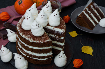 Halloween layer chocolate cake with white chocolate cream and meringue ghosts on top. Food idea for...