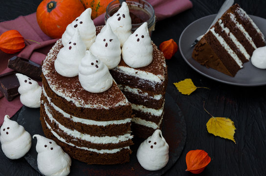 Halloween layer chocolate cake with white chocolate cream and meringue ghosts on top. Food idea for halloween party.