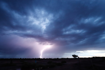 Naklejka na ściany i meble Lightning during a severe thunderstorm in the sunset light in the arid landscape of the Atacama desert, Chile