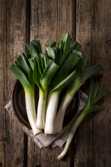 Leek on a plate on a wooden table, top view