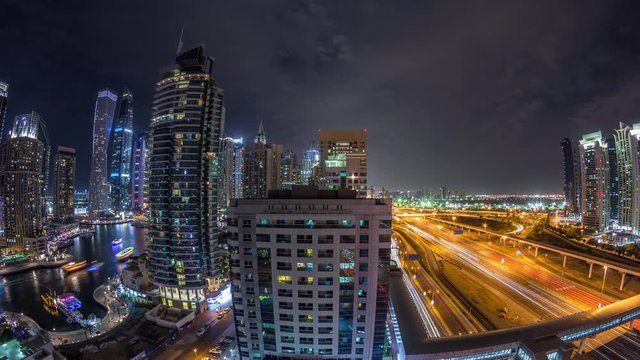 Aerial panoramic view to Dubai Marina skyscrapers and Sheikh Zayed road night timelapse, Dubai. Traffic, bridges and metro line. United Arab Emirates