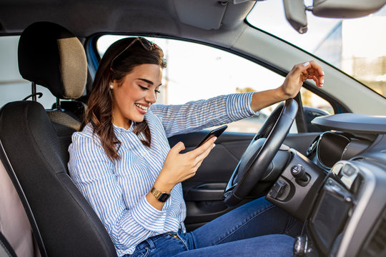 Woman driver using a smart phone in car. Woman driver using a smart phone in car. Leisure, road trip, technology, travel and people concept - Happy woman driving car with smarhphone