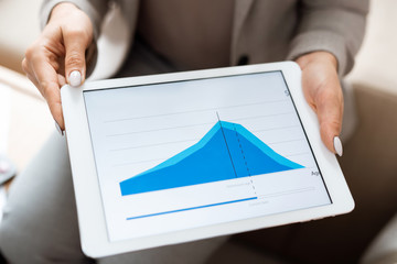 Hands of real estate agent holding tablet with blue financial graph on display