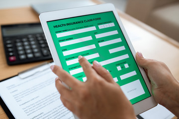 Electronic form of health insurance in digital tablet held by human hands