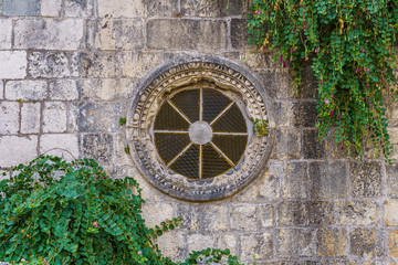 Fototapeta na wymiar wall of building with a round window, entwined with ivy