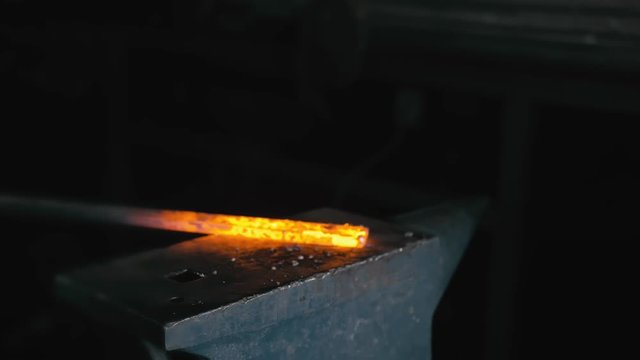 Forge workshop. Smithy manual production. Hands of smith with hammer hit on glowing hot metal, on the anvil, the forging process.