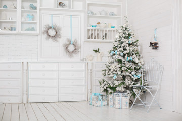 Stylish Christmas interior with an elegant blue decorations. Comfort home. White iron chair. Christmas tree with presents underneath in living room