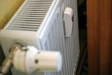 White radiator in an apartment with thermostat and temperature sensor