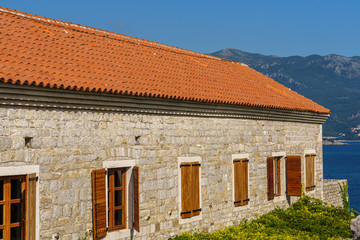 building is made of stone with a tiled roof and wooden shutters on the windows