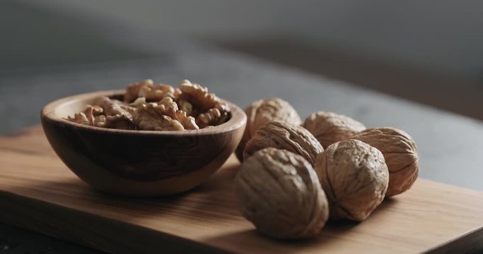 Slow motion man hand put bowl with walnut kernels on terrazzo countertop