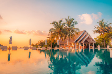 Luxury summer travel and vacation. Beautiful poolside and sunset sky landscape. Luxurious tropical beach landscape, deck chairs and loungers and water reflection. - obrazy, fototapety, plakaty