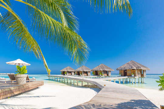 Maldives luxury water villas over white sand, blue sky. Amazing summer vacation travel destination, tropical landscape. Luxurious Maldives island landscape