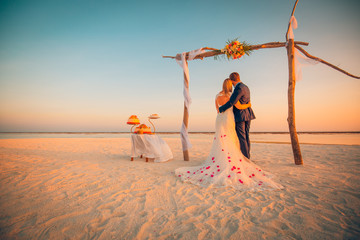 The bride and groom under archway on beach. Romantic wedding background. Romantic married couple,...