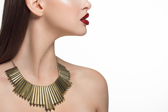 Close up glamor image of a female predator with a bite of scarlet lips. On the neck of the girl gold jewelry and sparkles on the body. Straight laminated hair. Spa care. Beauty sexy woman