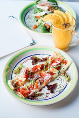 Tea and Pancakes with red caviar in colorful plate on white table in restaurant. Business lunch. Maslenitsa. Close-up. Space