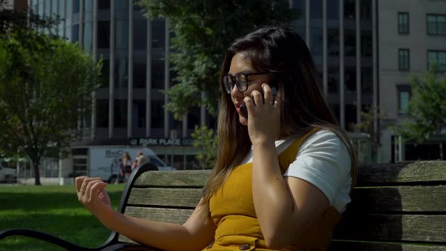 4k Woman in the Summer Heat Sits on a Bench and Talks to her family on the phone