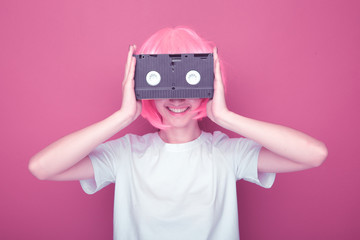 Fototapeta premium Young girl 90s and VHS cassette on pink background.