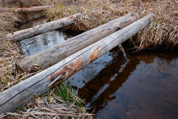 Improvised wooden bridge over small stream in the early spring forest