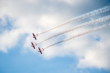 Aerobatics, air show. Aircraft team performing in the sky with old airplanes and drawing lines, white clouds and blue sky