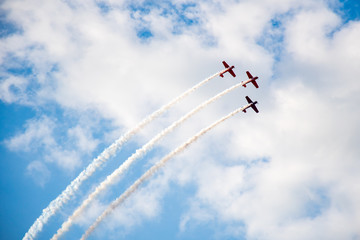 Aerobatics, air show. Aircraft team performing in the sky with old airplanes and drawing lines, white clouds and blue sky