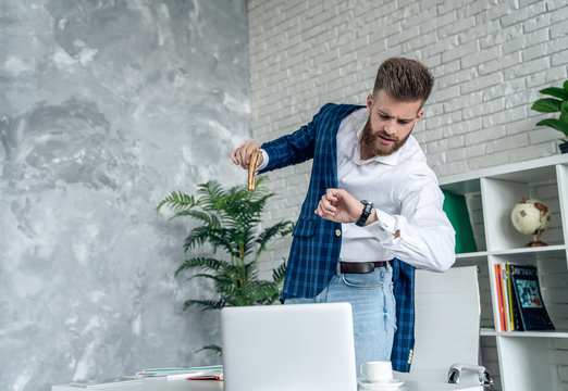 Young businessman is having a snack oh his way to meeting. He is very busy, rushing eat before he goes. checking time on his watch