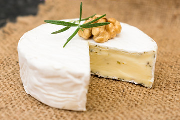 Camembert cheese with herbs, decorated   with a sprig of rosemary and walnut. Close-up.