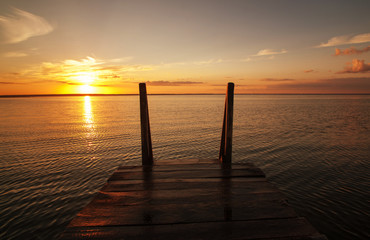 Fototapeta na wymiar Beautiful landscape of pier on lake at sunset. Silence and harmony of nature