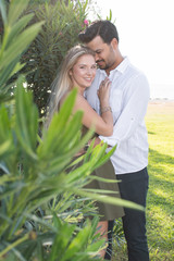 Obraz premium Man's head touching woman's head looking down. Woman facing camera. In-love and happy mixed race couple. Blonde woman and Turkish (Middle Eastern) man in love. Romantic lovers on vacation.