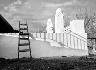 Ladder on a white wall. Cemetery. Black and white picture