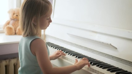 Little girl studying to play the piano at home. Preschool child having fun with learning to play music instrument. Education, skills concept.