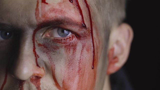 Halloween man portrait. Guy with dripping blood on his face. Scary makeup