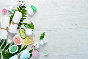 Spa. Towels, face cream, tropical leaves. On a white wooden background. Flat lay.