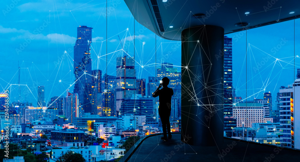 Poster businessman standing using smart phone in modern space watching city night view.business with ambiti