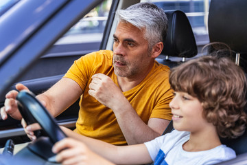 Handsome man teaching his son how to drive