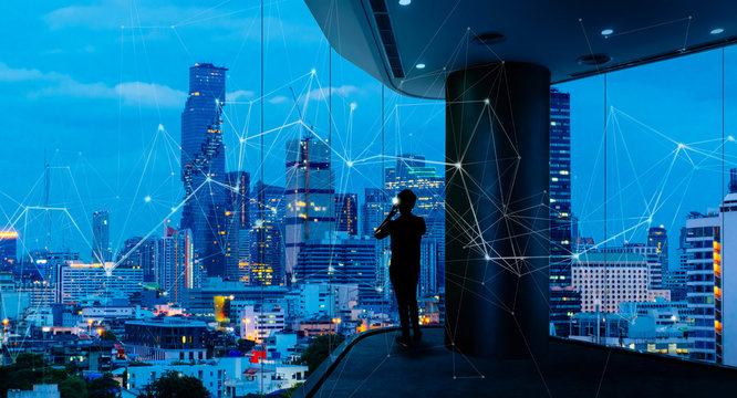 Businessman standing using smart phone in modern space watching city night view.Business with ambition and vision concept.and wireless network low poly line.