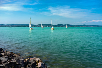 Sail Boats on the blue Lake Balaton Hungary with rocks on the coast