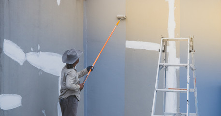 Man paints the walls in gray color, Focus on the roller. Painting and repair of the room.