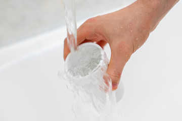 hand holding a glass and pouring pure water in it to drink.