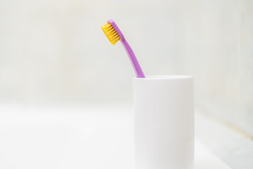 a single simple toothbrush in a glass in bathroom