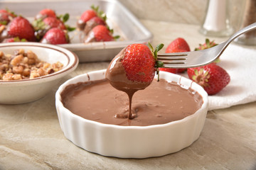 Dipping a strawberry in chocolate sauce
