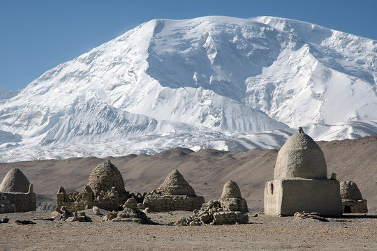 Mountainous landscape. Old kyrgyz cemetery on the background of Muztagh Ata mountain (7546 m). Pamir mountains, outskirts of Kashgar, Xinjiang, China, Asia.