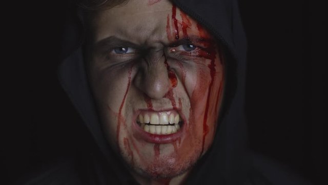 Man executioner Halloween makeup and costume. Guy with blood on his face