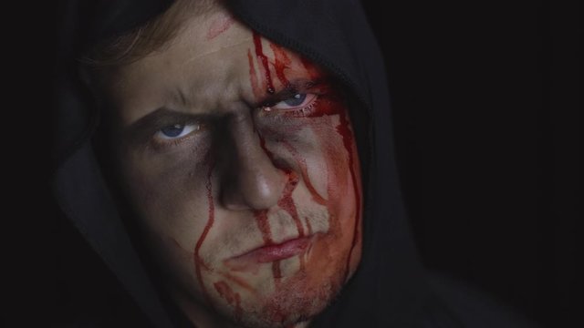 Man executioner Halloween makeup and costume. Guy with blood on his face