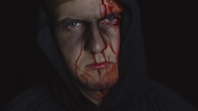 Man executioner Halloween makeup and costume. Guy with blood on his face