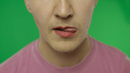Bearded man with painted lips licks them sexually. LGBT community. Transsexual