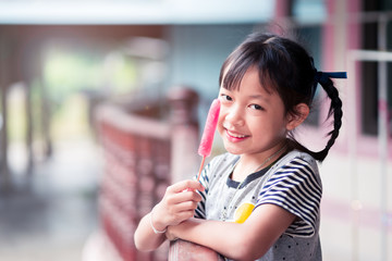 Beautiful asian little girl eats ice-cream in the summer at home