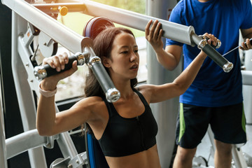 muscular young sporty woman exercising chest press machine with personal trainer for perfect body in fitness gym, bodybuilder, healthy lifestyle, exercise fitness, workout and sport training concept