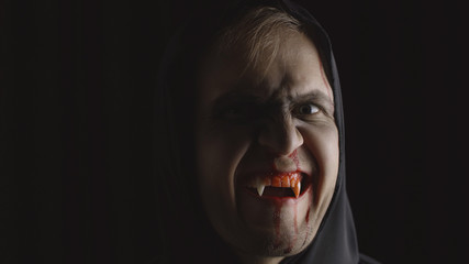 Man vampire Halloween makeup and costume. Guy with blood on his face